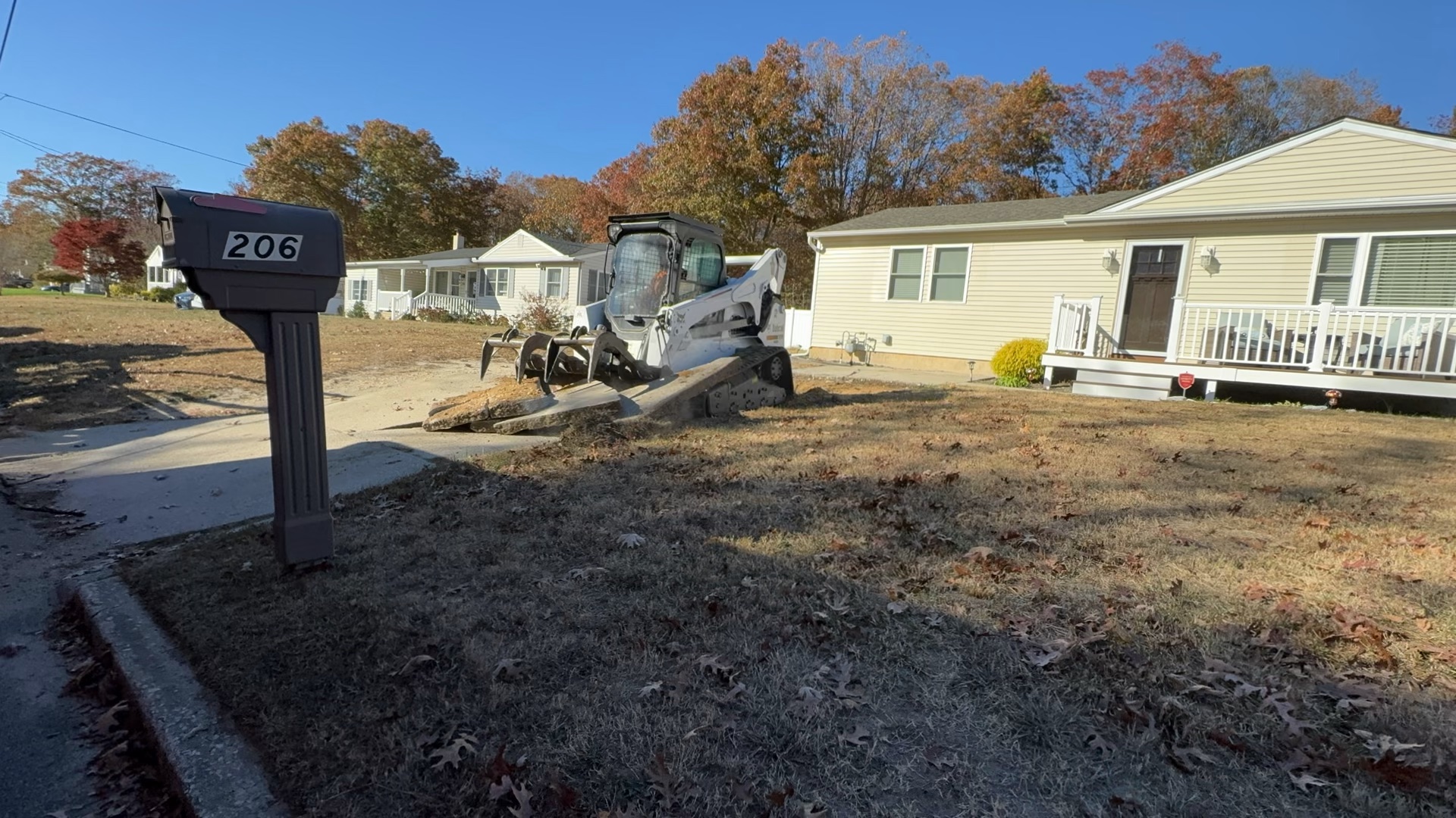 Skid steer removing broken concrete from a residential front yard